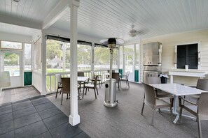 Ein überdachter Patio-Bereich mit Tisch und Stühlen, einem Deckenventilator und Blick auf die Umgebung.