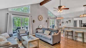A spacious living room with a sofa, coffee table, and a dining area with stools. - Hokie Hideaway- Pet-friendly home with a fire-pit to enjoy with the family. (Huddleston)