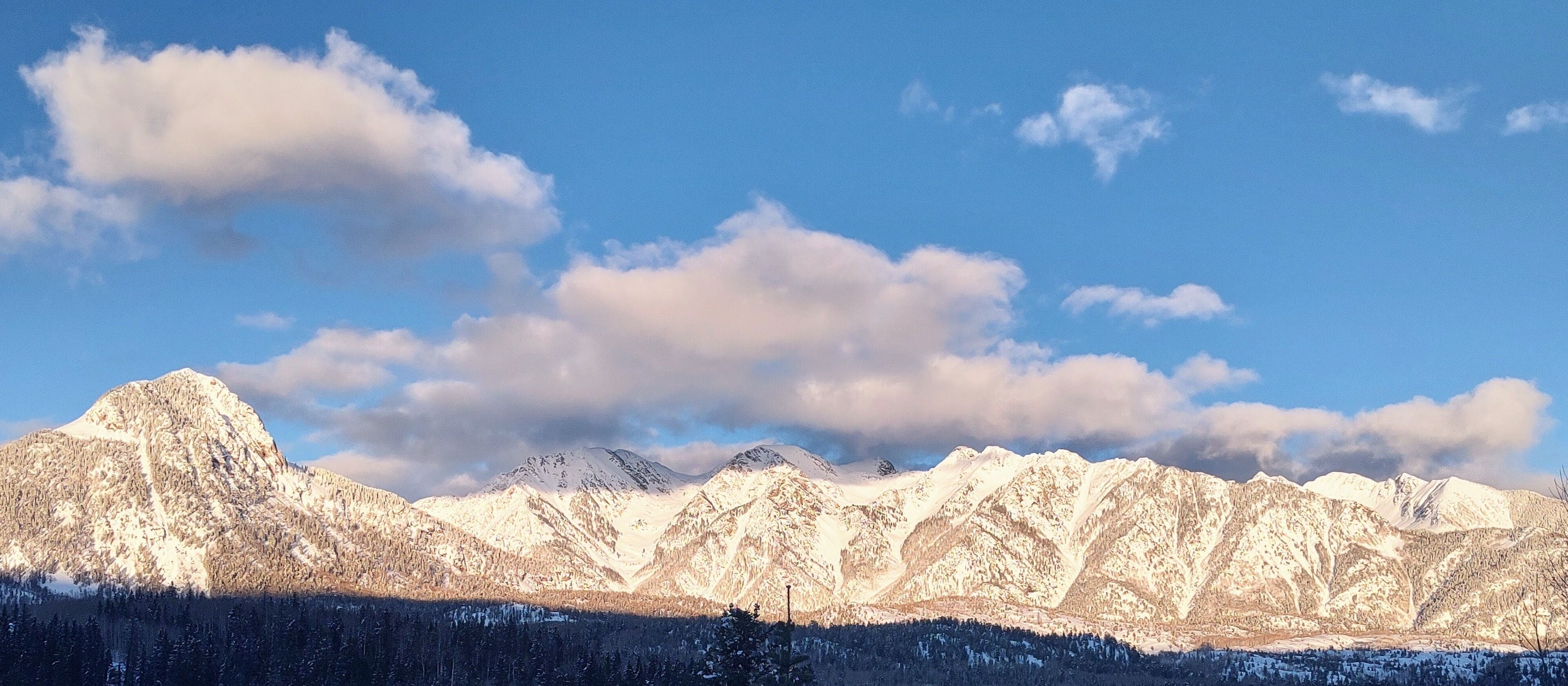 Ein Gebirge mit schneebedeckten Gipfeln und blauem Himmel.
