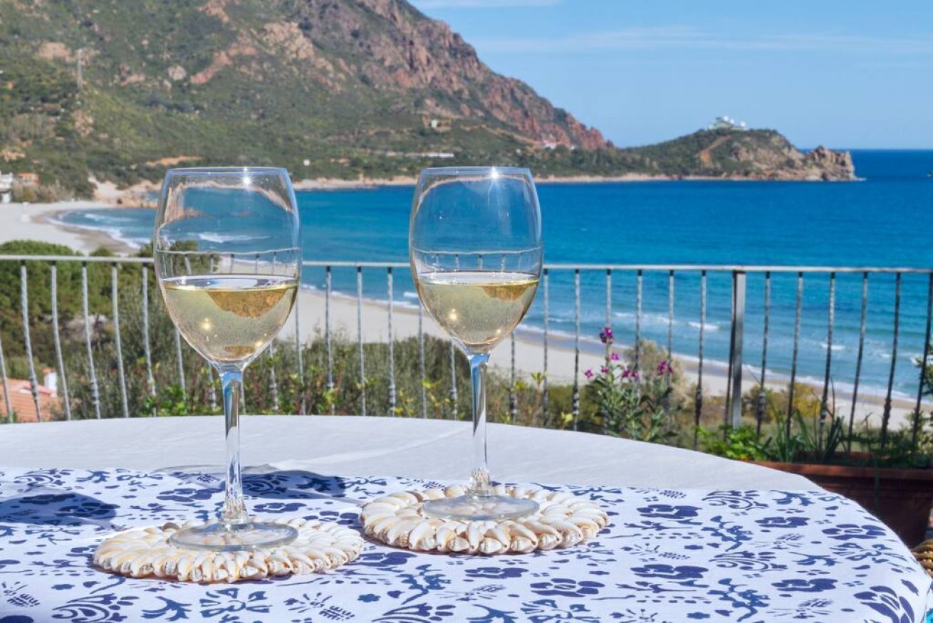 Two wine glasses on a table with a coastal view.