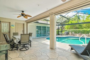A covered patio with a pool, outdoor furniture, and a ceiling fan.