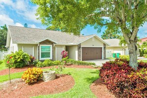 A single-story house with a garage, surrounded by landscaped gardens and a large tree. - Florida Vacation home with Pool- Near Naples (Bonita Springs)