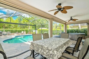 A covered outdoor area with a pool, a table with a tablecloth, chairs, ceiling fans, and a hot tub. - Florida Vacation home with Pool- Near Naples (Bonita Springs)