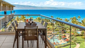 Un balcone con un tavolo apparecchiato per due, con vista su una piscina e l'oceano.