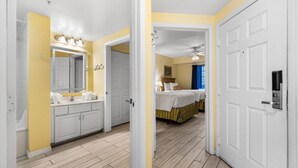 A hotel room with a bathroom, a bed, and a door. - Serene Oceanfront Getaway: 1BR with Private Balcony at Wyndham Oceanwalk (Daytona Beach)