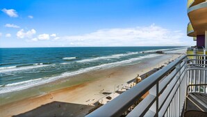A beach view from a balcony with a clear sky, a pier in the distance, and a sandy beach. - Serene Oceanfront Getaway: 1BR with Private Balcony at Wyndham Oceanwalk (Daytona Beach)