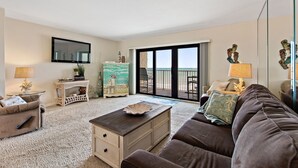 Un salon avec un canapé, une table basse, un téléviseur et un balcon offrant une vue agréable.