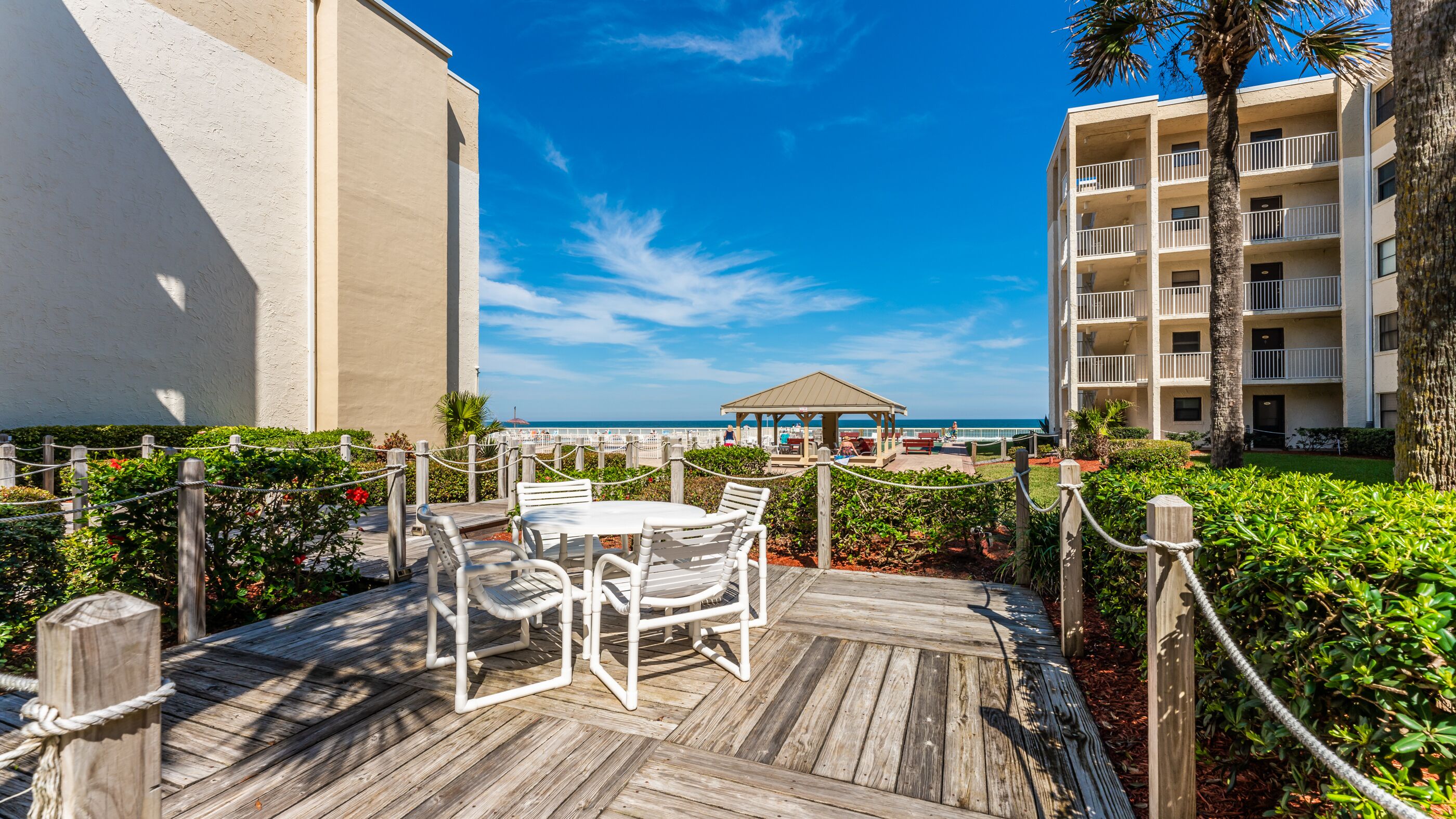 A wooden deck with a table and chairs, a gazebo, and a view of the ocean.