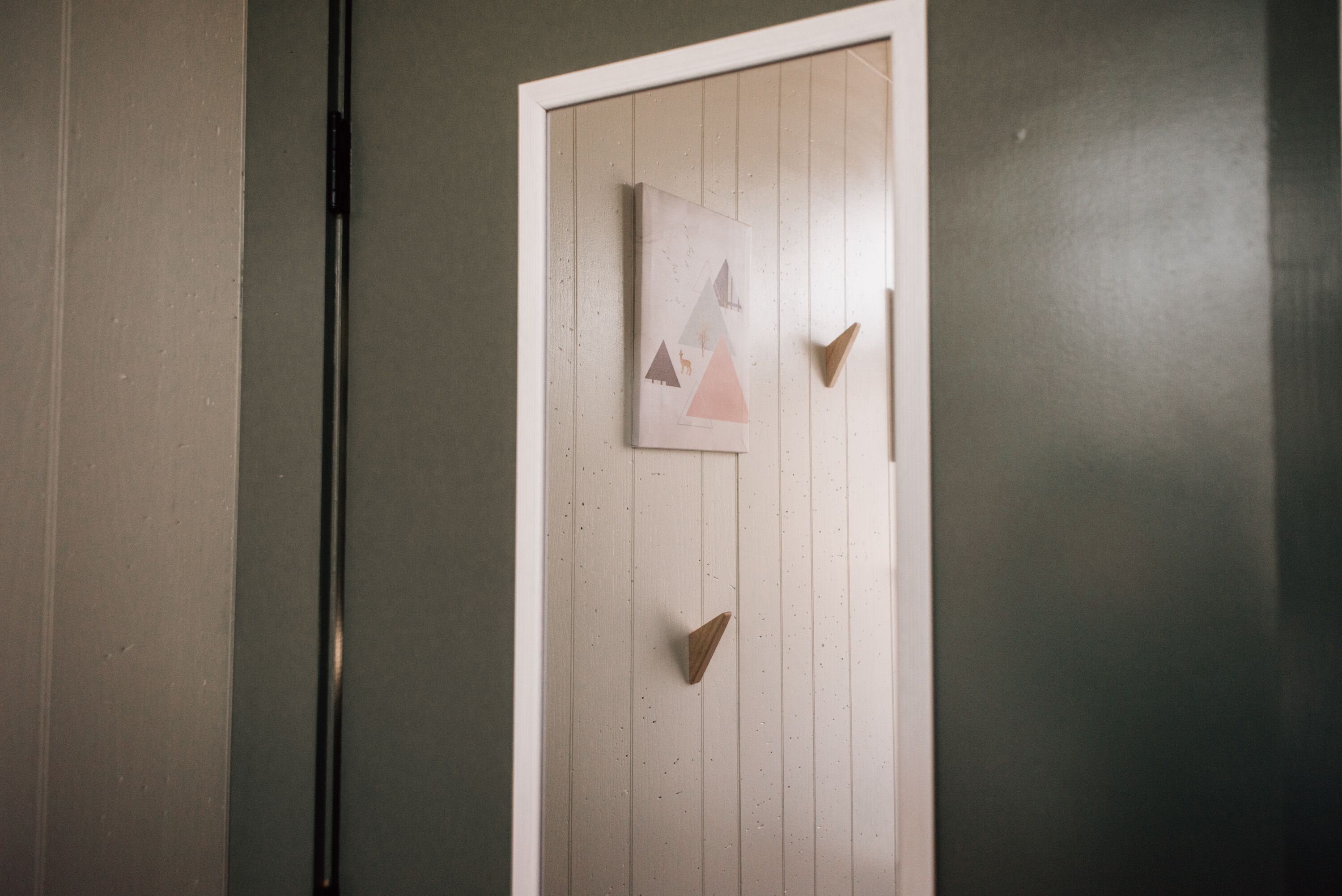 A door with a wooden panel design and a framed picture of a mountain scene.