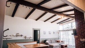 A spacious living area with a wooden bench, a sofa, and a coffee table. There is a door leading to another room, and a brick wall on one side. - Multi-Family Cabin @ Shenandoah Bryce Resort (Basye)
