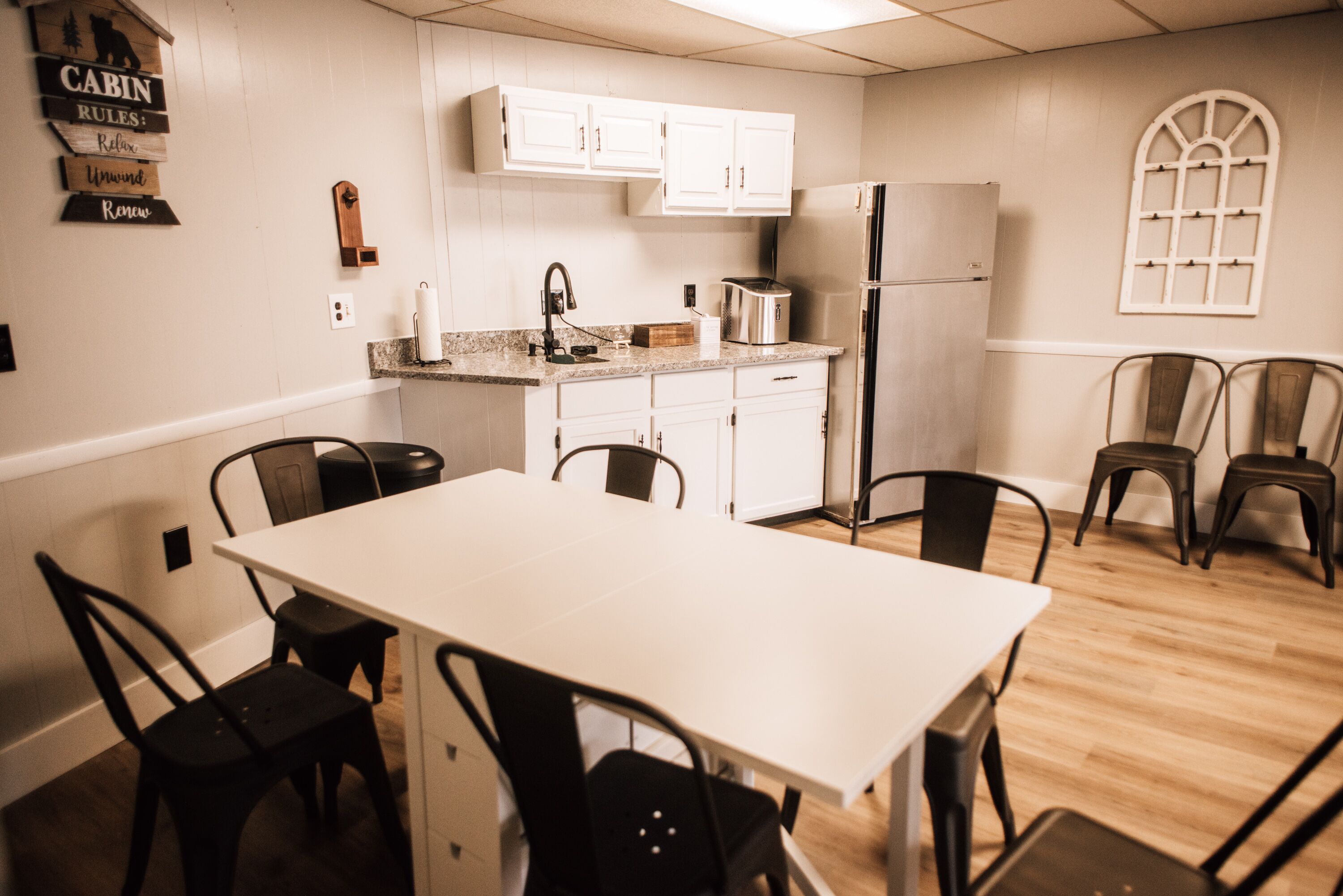 A modern kitchen with white cabinets, a stainless steel refrigerator, a toaster, and a dining table with chairs.