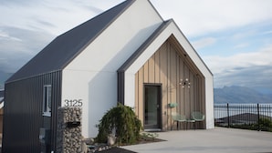 A modern building with a sloped roof, a stone mailbox, and a small garden with a potted plant.