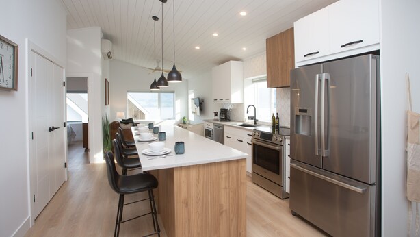 A modern kitchen with a large island, stainless steel appliances, and pendant lighting.