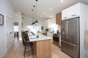 A modern kitchen with a large island, stainless steel appliances, and pendant lighting.