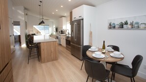 A modern kitchen with a central island, stainless steel appliances, and a dining area with a round table and chairs.