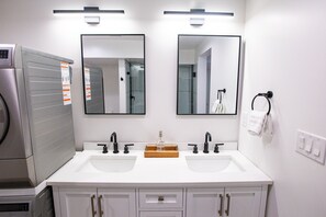 Une salle de bain moderne avec deux lavabos, un sèche-cheveux et un miroir.