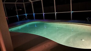 Ein Swimmingpool mit Glasumrandung, umgeben von einem weißen Zaun.