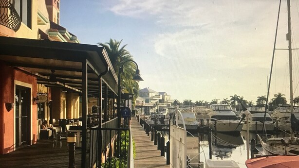 Ein Holzsteg mit einer Reihe von Gebäuden an einer Seite und einem Hafen mit Booten an der anderen.