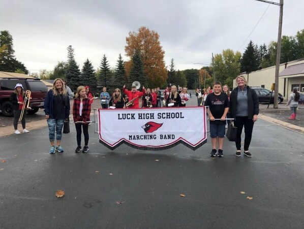 A group of people holding a banner for Luck High School Marching Band.