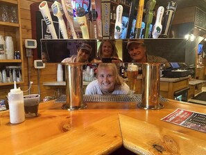 A bar area with a wooden counter, a large mirror reflecting the bar, and various bottles and glasses on shelves. - Lucky View Lodge Log Cabin on Big Butternut Lake Luck, WI 3 acre 300ft lakeshore (Luck)