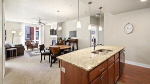 Una cocina moderna con encimeras de granito, gabinetes de madera e iluminación colgante.
