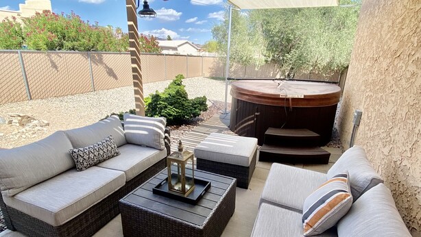 Een terras buiten met een overdekte zithoek, een jacuzzi en een decoratieve lantaarn.