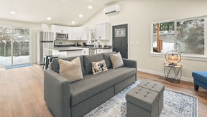 A modern kitchen with white cabinets, stainless steel appliances, and a black door.