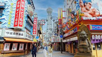A bustling street with shops and a prominent statue of a figure.