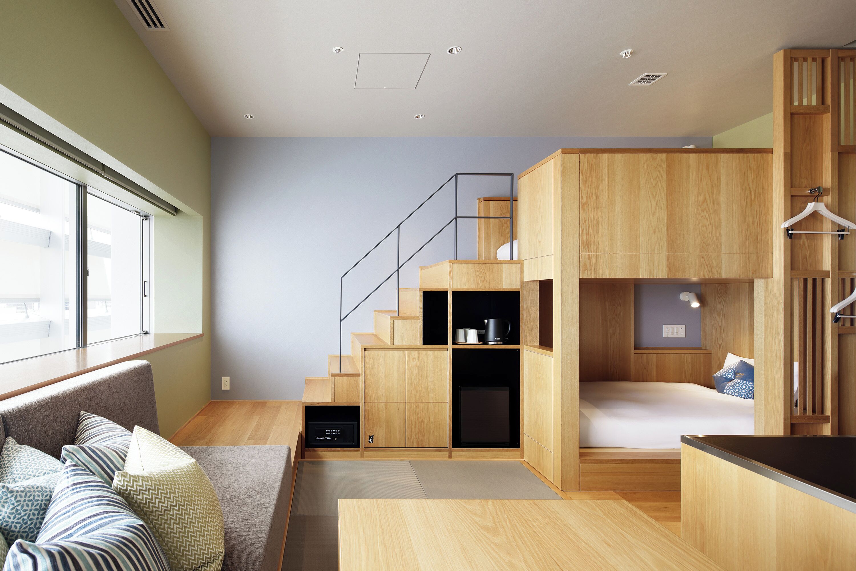 Quarto moderno e compacto com cama embutida, móveis de madeira, escada e janela que proporciona iluminação natural.
