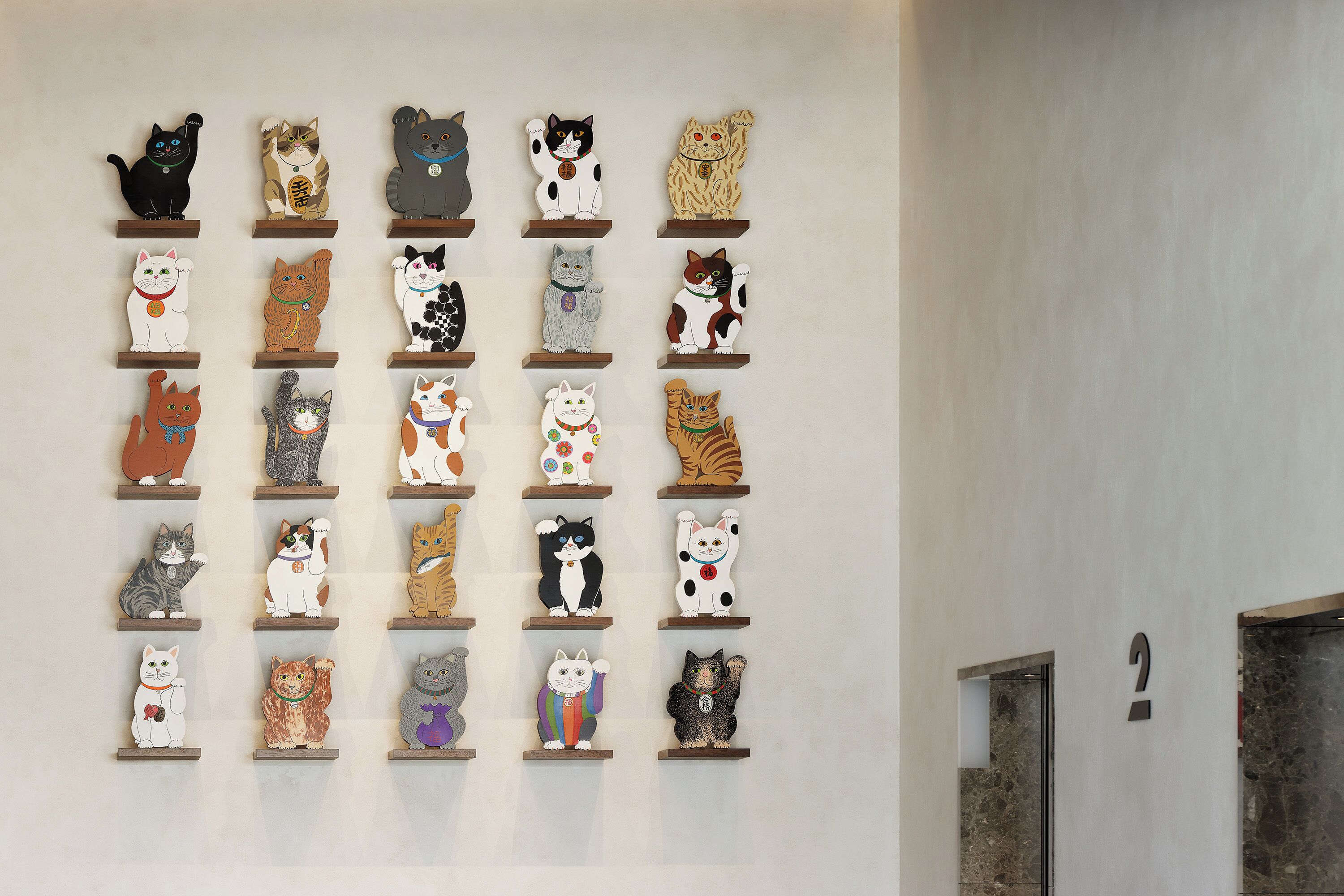 Una pared con varios estantes que exhiben diferentes figuras de gatos.