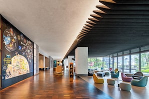 Een ruime hal met een houten vloer, een kleurrijke muurschildering van een kaart en een zithoek met moderne stoelen.