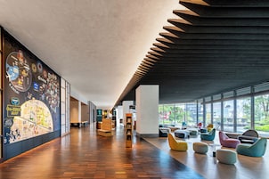 A spacious lobby with a wooden floor, a colorful map mural, and a seating area with modern chairs.
