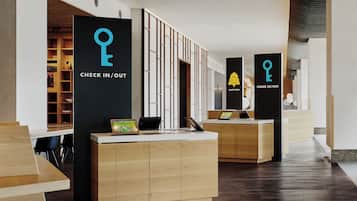 Ein Empfangsbereich mit einer Rezeption für Check-in und Check-out, Holzschränken und einem Schreibtisch mit Computer und Tablet.