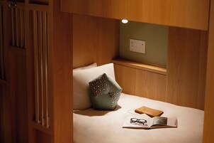 A neatly made bed with a pillow, a book, and glasses on it.