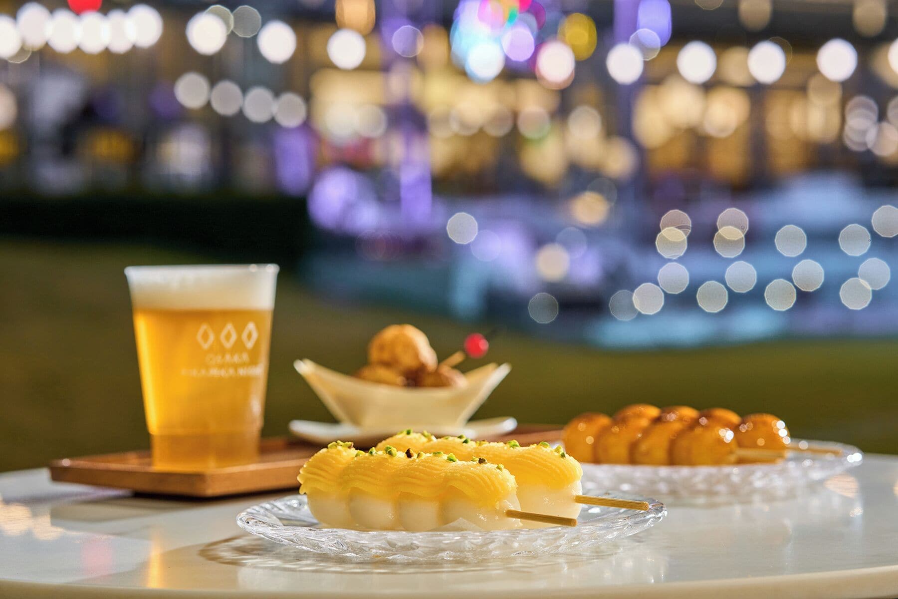 A table with a glass of beer, a dessert with nuts, and a plate of sweets.