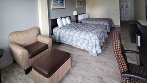 Ein Hotelzimmer mit einem Bett, zwei Stühlen, einem Schreibtisch und einem Deckenventilator.