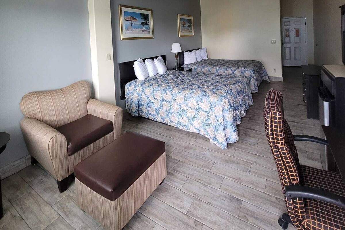 Habitación de hotel con cama, dos sillones, un escritorio y ventilador de techo.