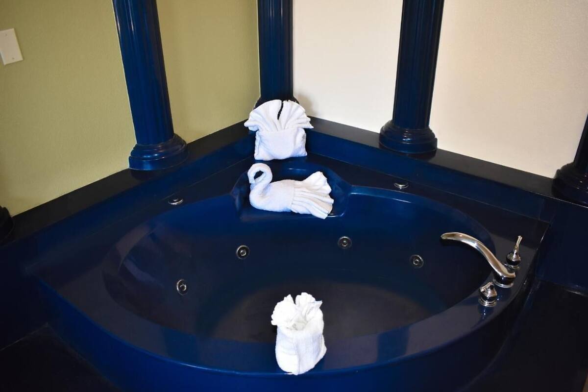 Una bañera grande de azul oscuro con tres toallas blancas dobladas en diferentes formas.