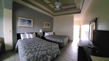 Una habitación de hotel con dos camas, un ventilador de techo y obras de arte en las paredes.