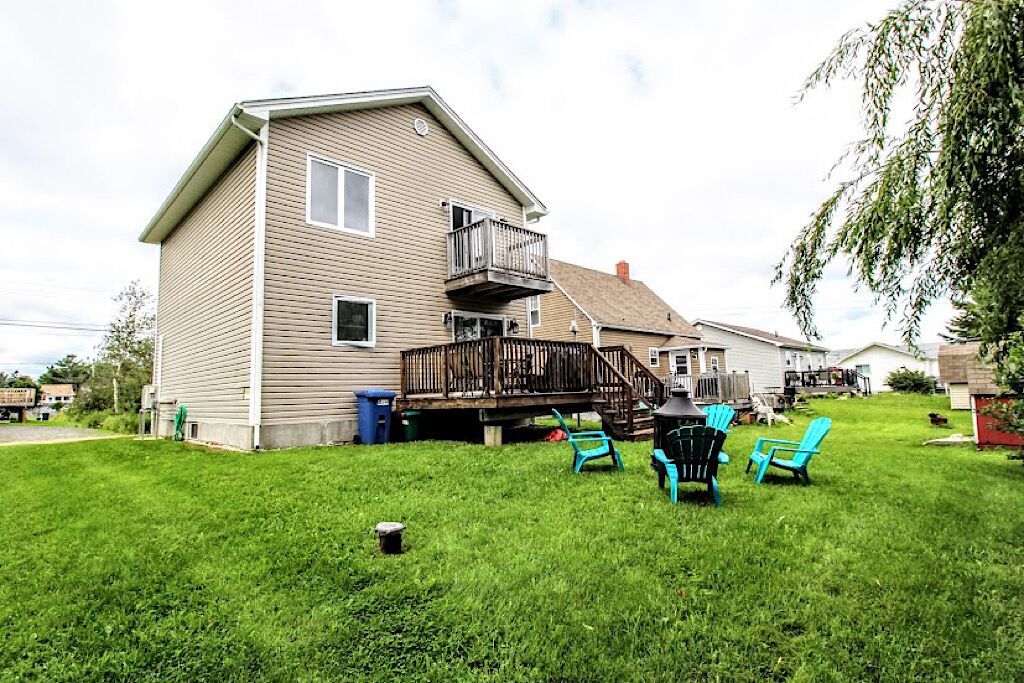 A two-story house with a wooden deck and outdoor seating area.