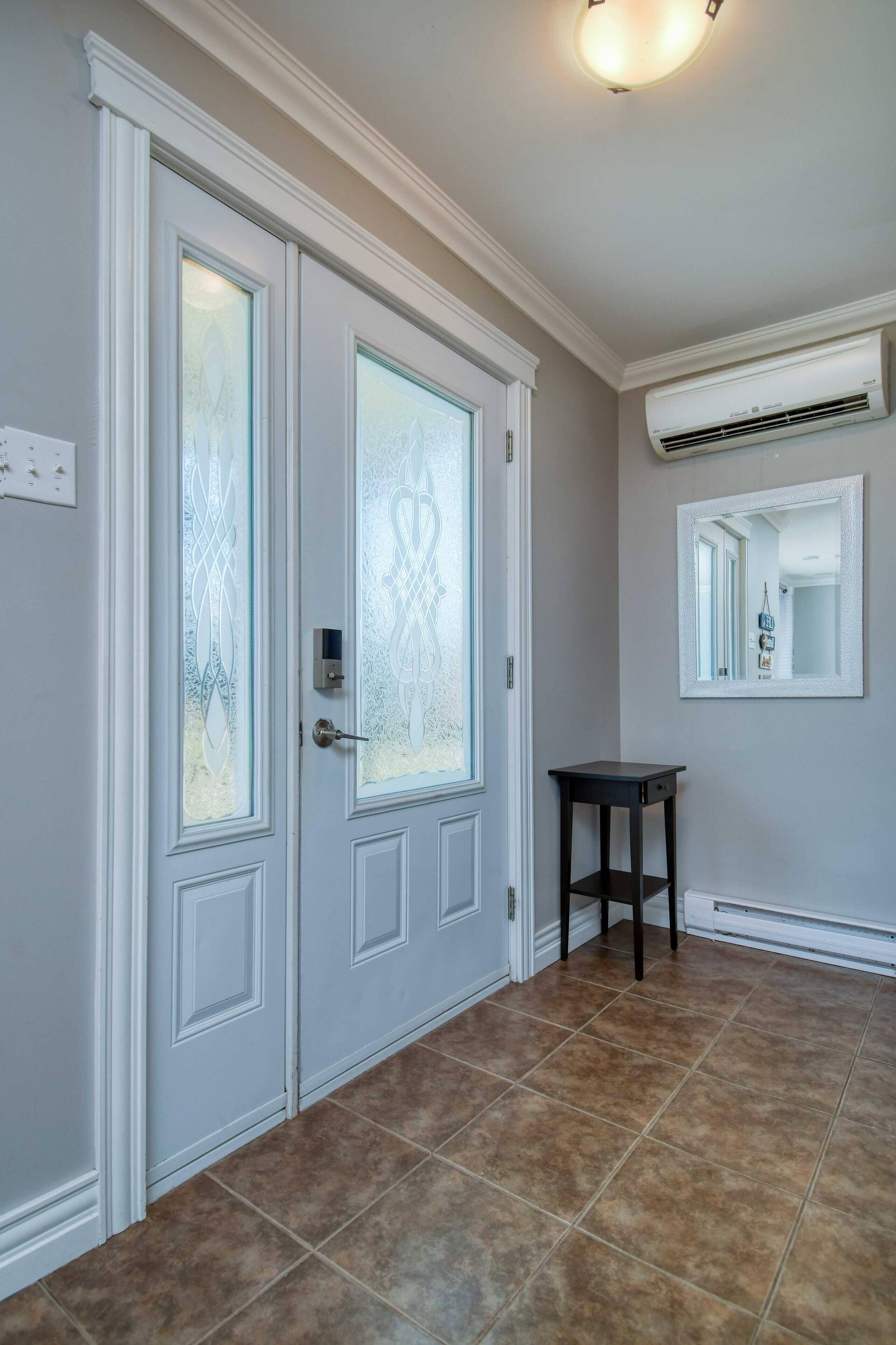 A hallway with double doors, a small table, and an air conditioning unit on the wall.