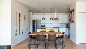 Una cocina moderna con armarios blancos, una mesa de comedor de madera y un conjunto de sillas marrón y negro.