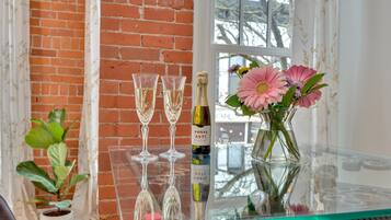 A glass table with two wine glasses, a bottle of wine, and a vase with flowers.
