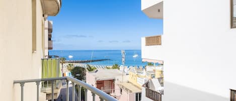 Un balcon donnant sur la mer, un escalier et un immeuble doté d’un balcon.