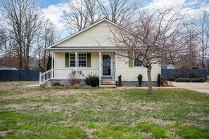 A single-story house with a front porch, a small tree, and a 'WELCOME' sign.