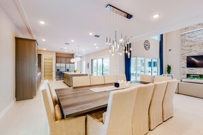 Una sala de estar moderna con comedor, cocina y pared de televisión.