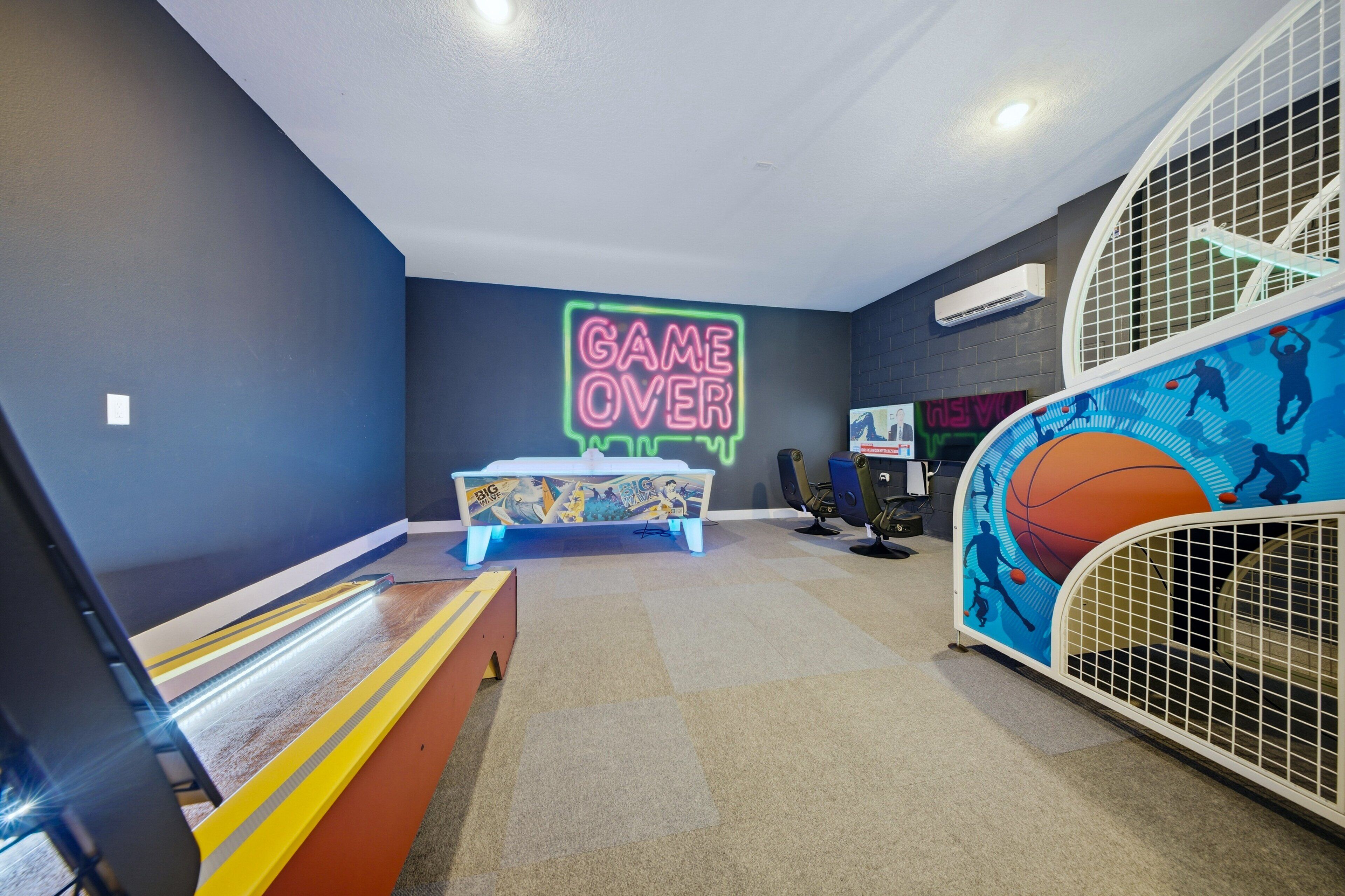 Ett rum med en neonreklamskylt som visar texten ”GAME OVER”, en säng, en lekhage med basketbollstema och ett litet bord.