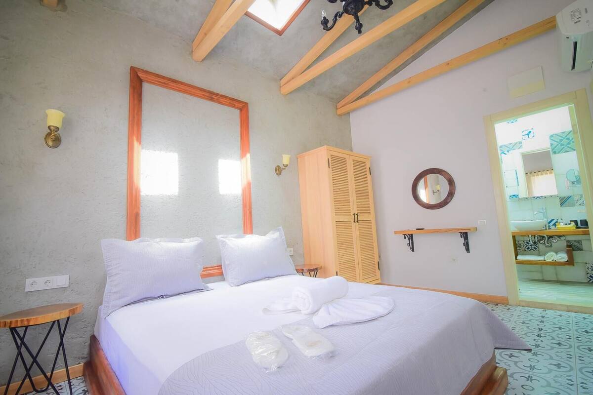A bedroom with a bed, a wardrobe, a mirror, and a bathroom visible through an open door.