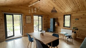 Eine geräumige Holzhütte mit Essbereich, Küche und großen Fenstern.