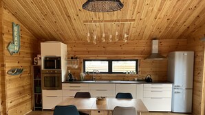 Eine gemütliche Küchenzeile im Blockhausstil mit Holzwänden, einer zentralen Kochinsel und modernen Geräten.